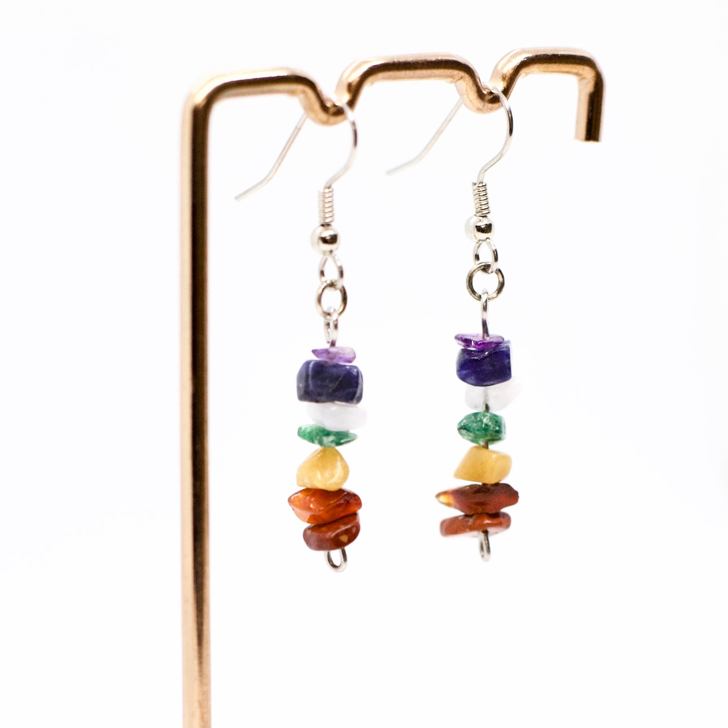 Close up of Chakra gemstone chip earrings on display stand with white background
