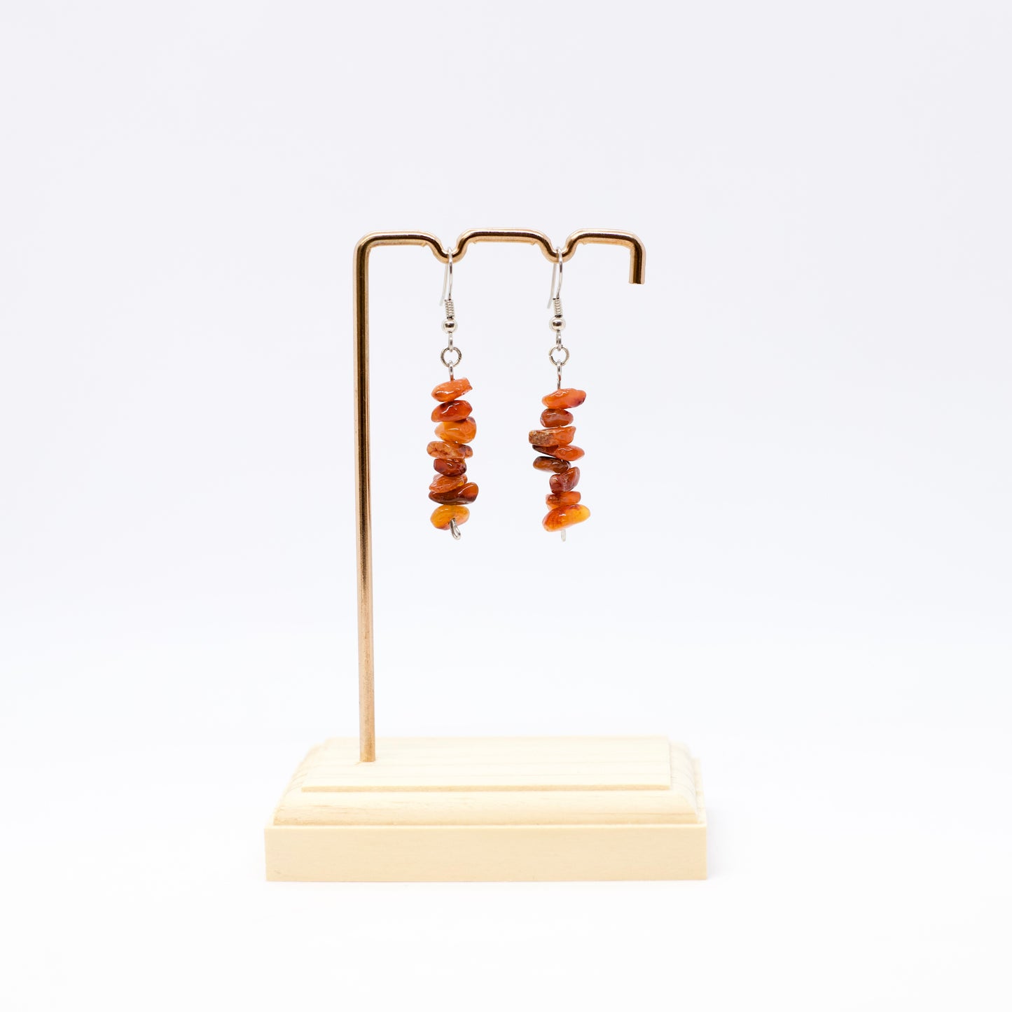 Carnelian gemstone chip dangle Earrings on display stand with white background