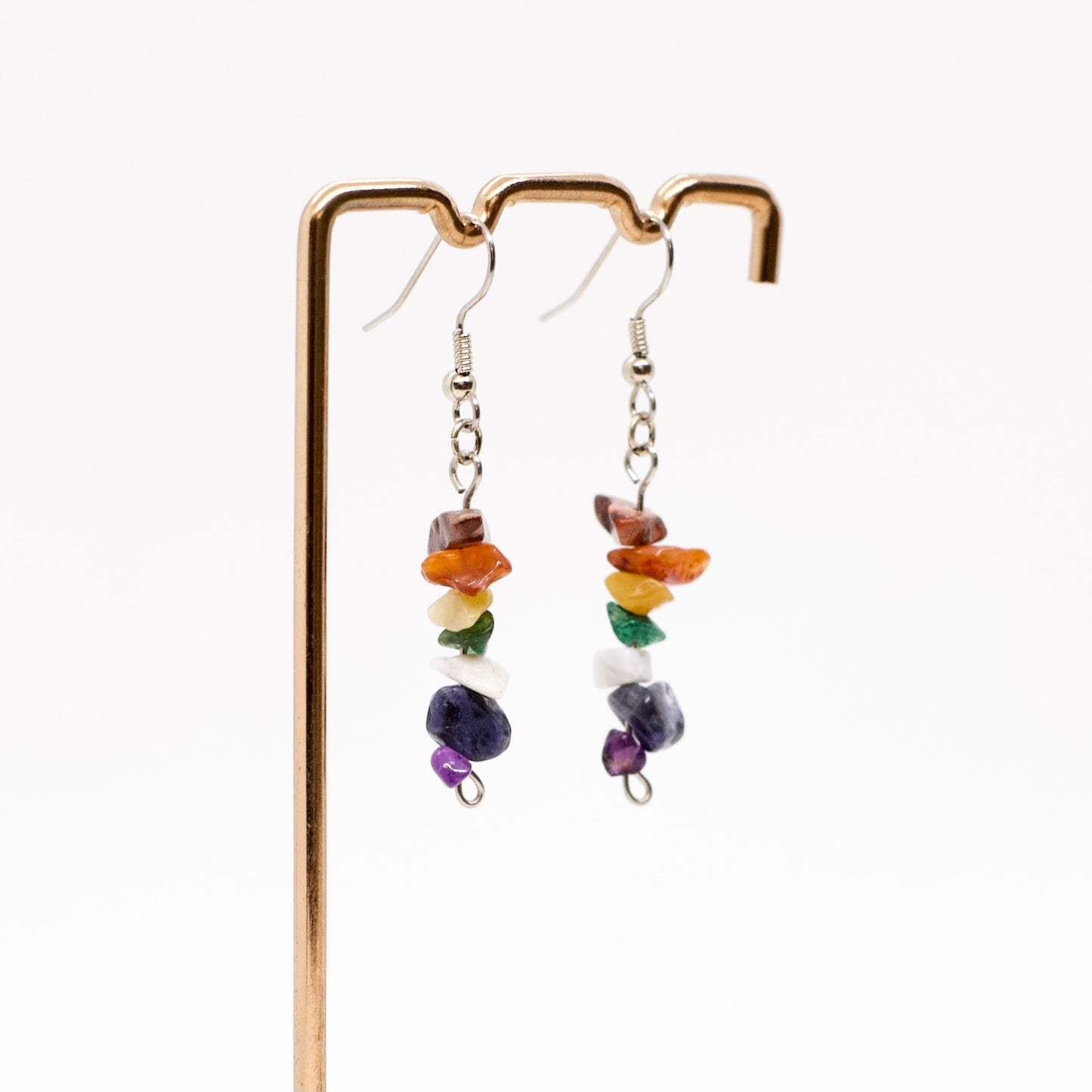 close up of Chakra gemstone dangle earrings on display stand with white background