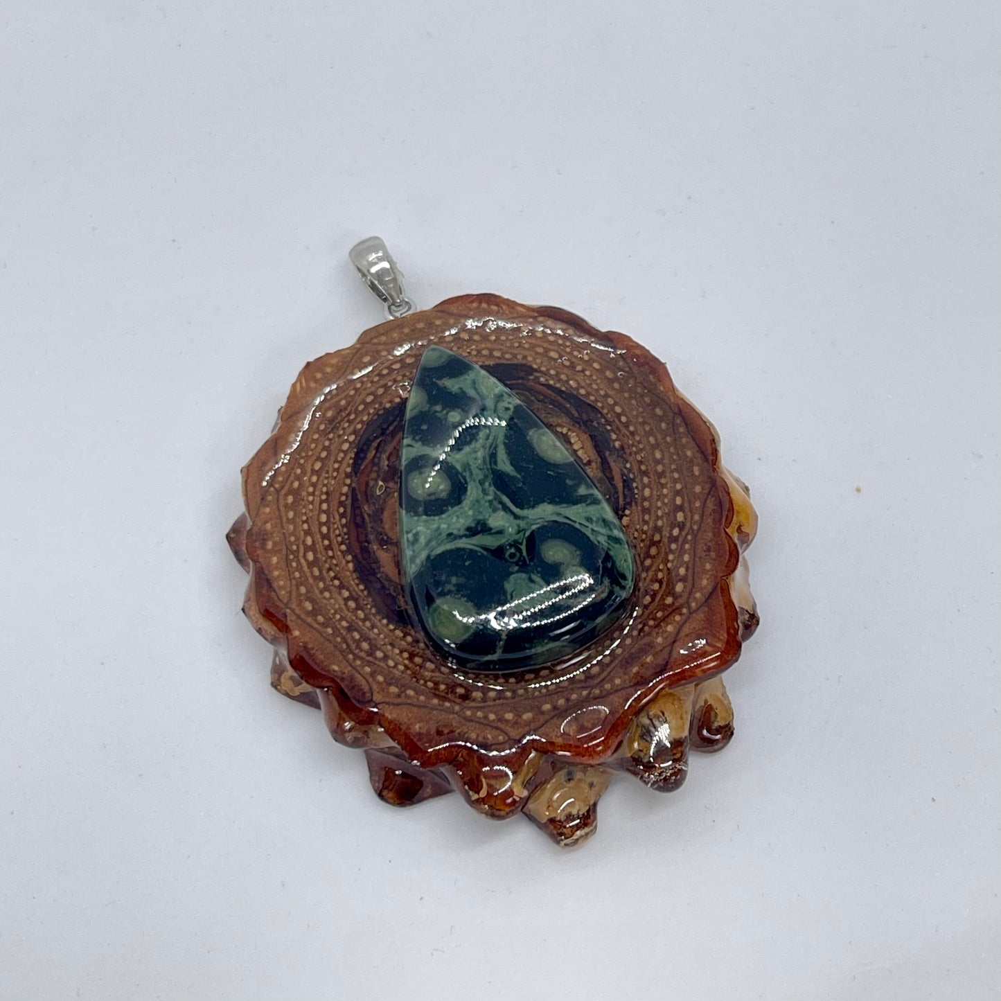 Ariel view of pinecone pendant with silver bail and kambaba jasper stone on white background