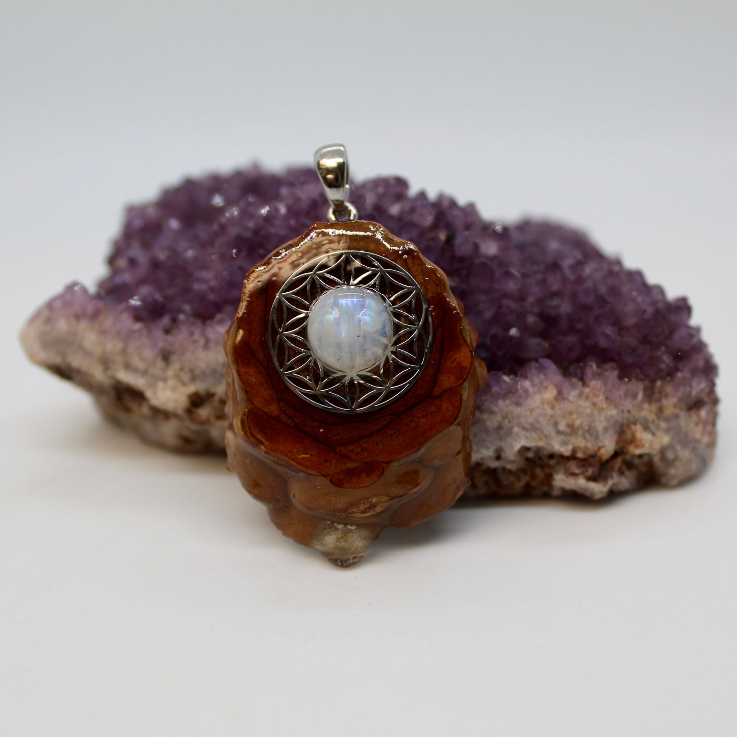 closeup view of pinecone pendant with moonstone on flower of life symbol