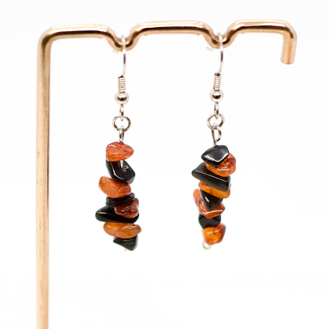 closeup of Carnelian and Obsidian gemstone chip dangle earrings on gold display stand