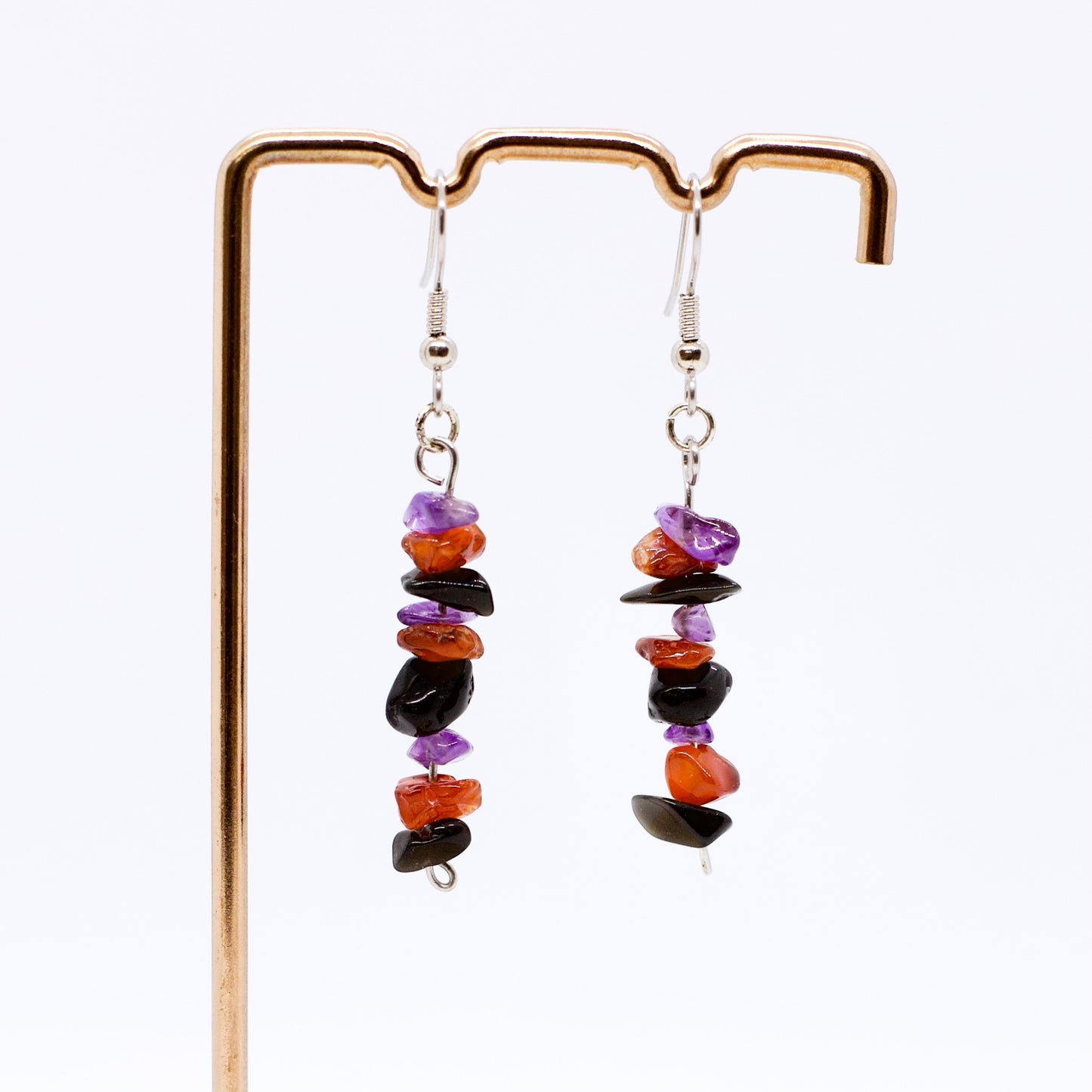 close up of Amethyst Carnelian Obsidian gemstone chip dangle earrings on stand with white background