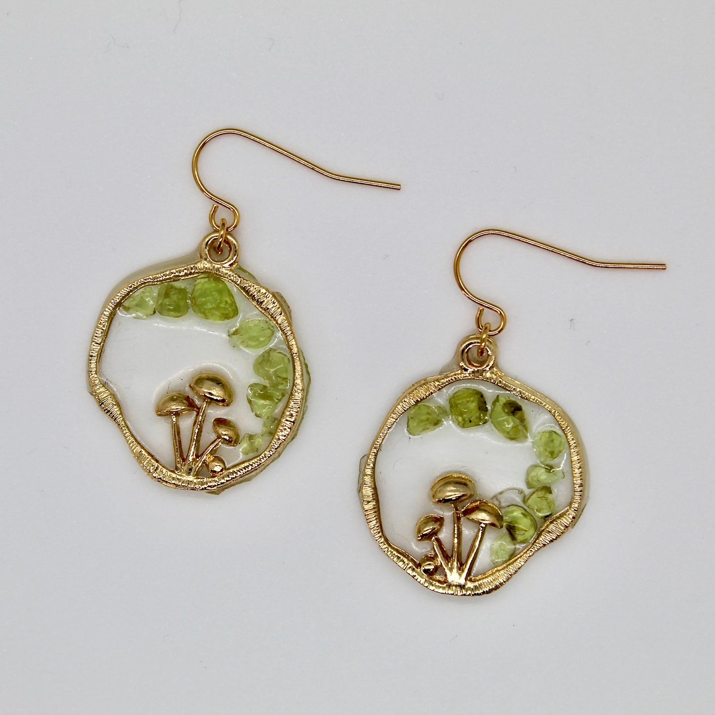 green gemstone earrings with gold mushrooms on white background