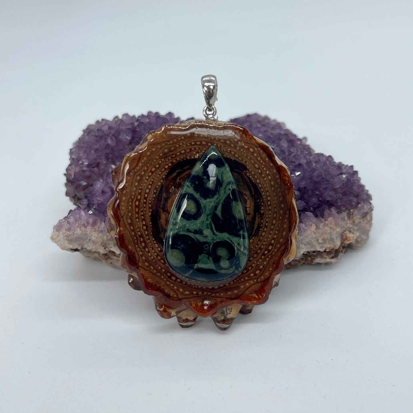 pinecone pendant with kambaba jasper stone and silver bail displayed on crystal 