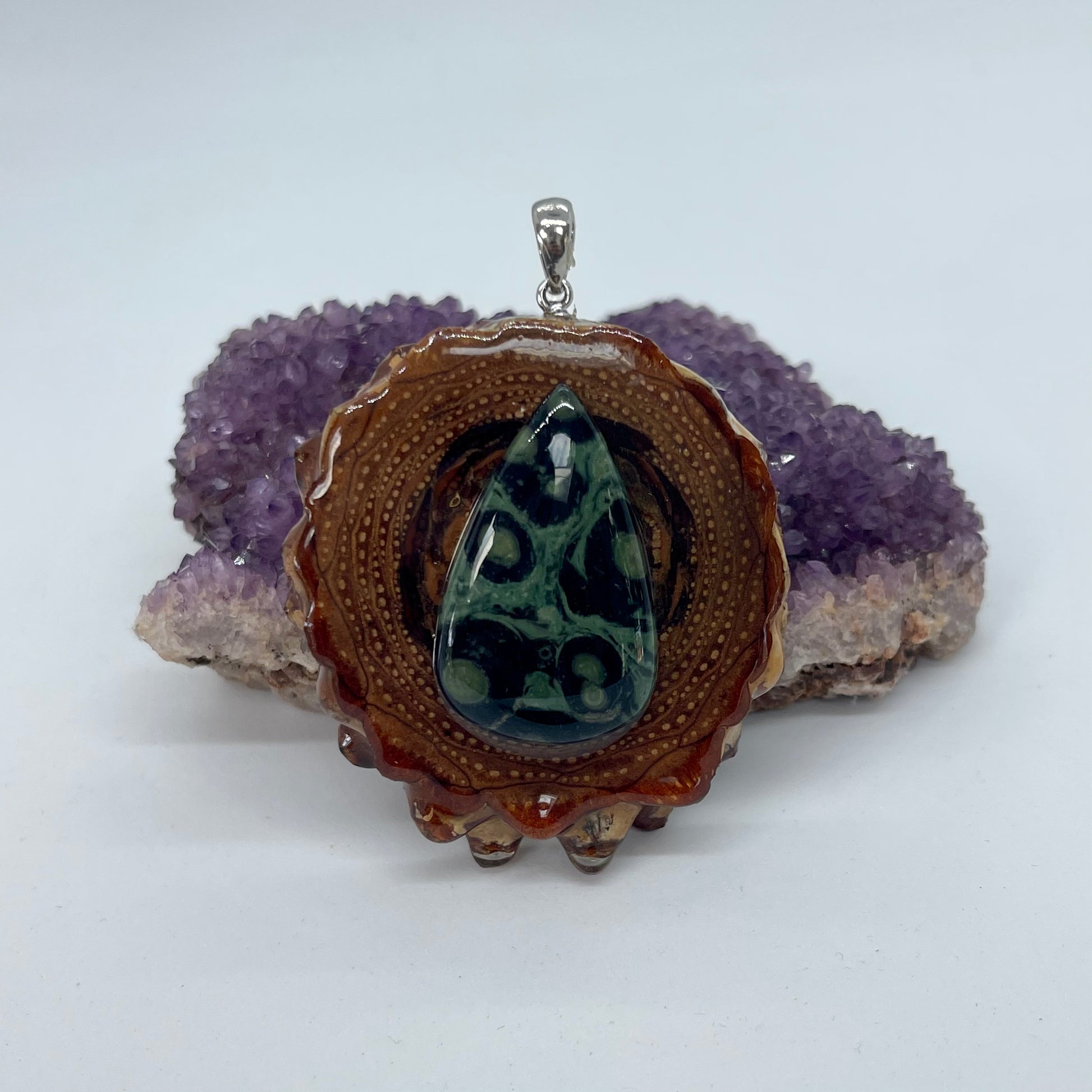 pinecone pendant with kambaba jasper stone and silver bail displayed on crystal 