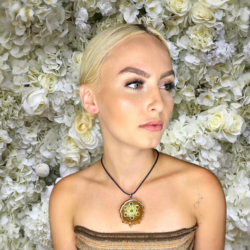 sideview model wearing pinecone pendant with opals in front of white flowers