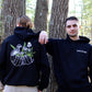 two models wearing black hoodie with white and green mushroom design 