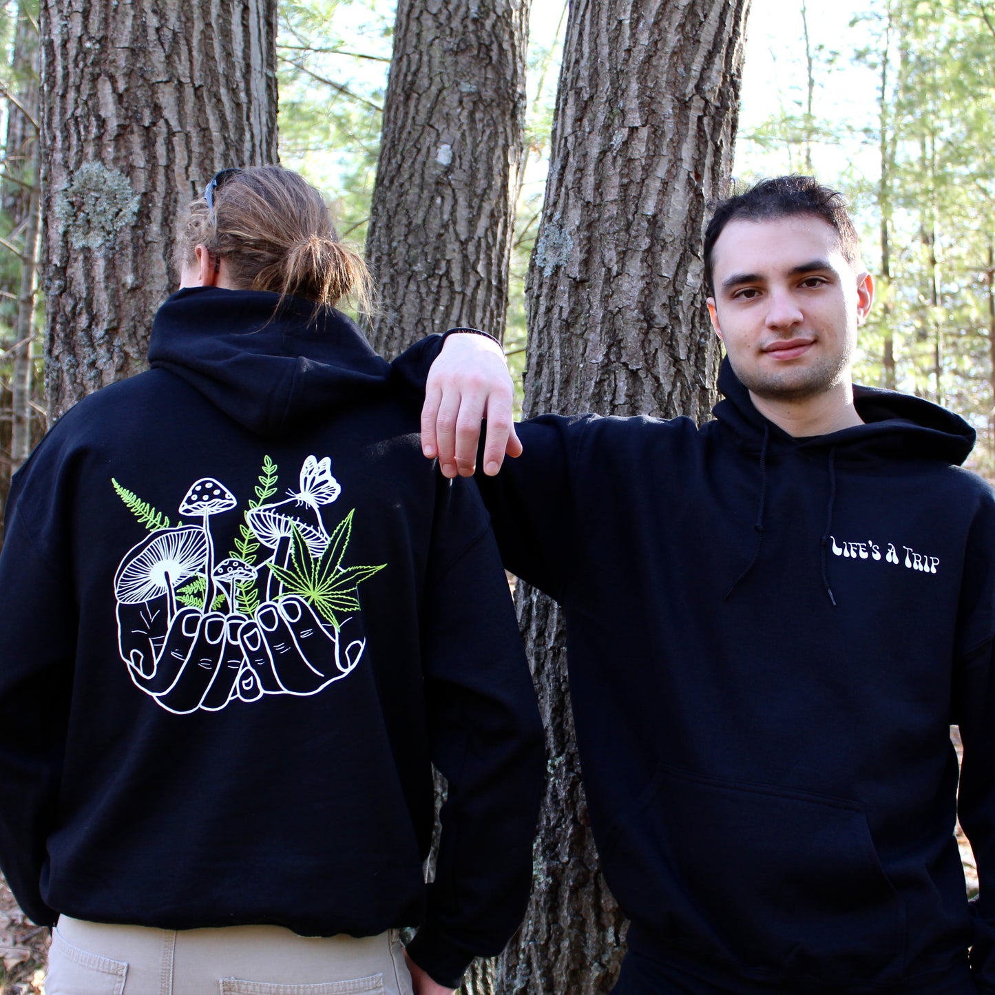 two models wearing black hoodie with white and green mushroom design 