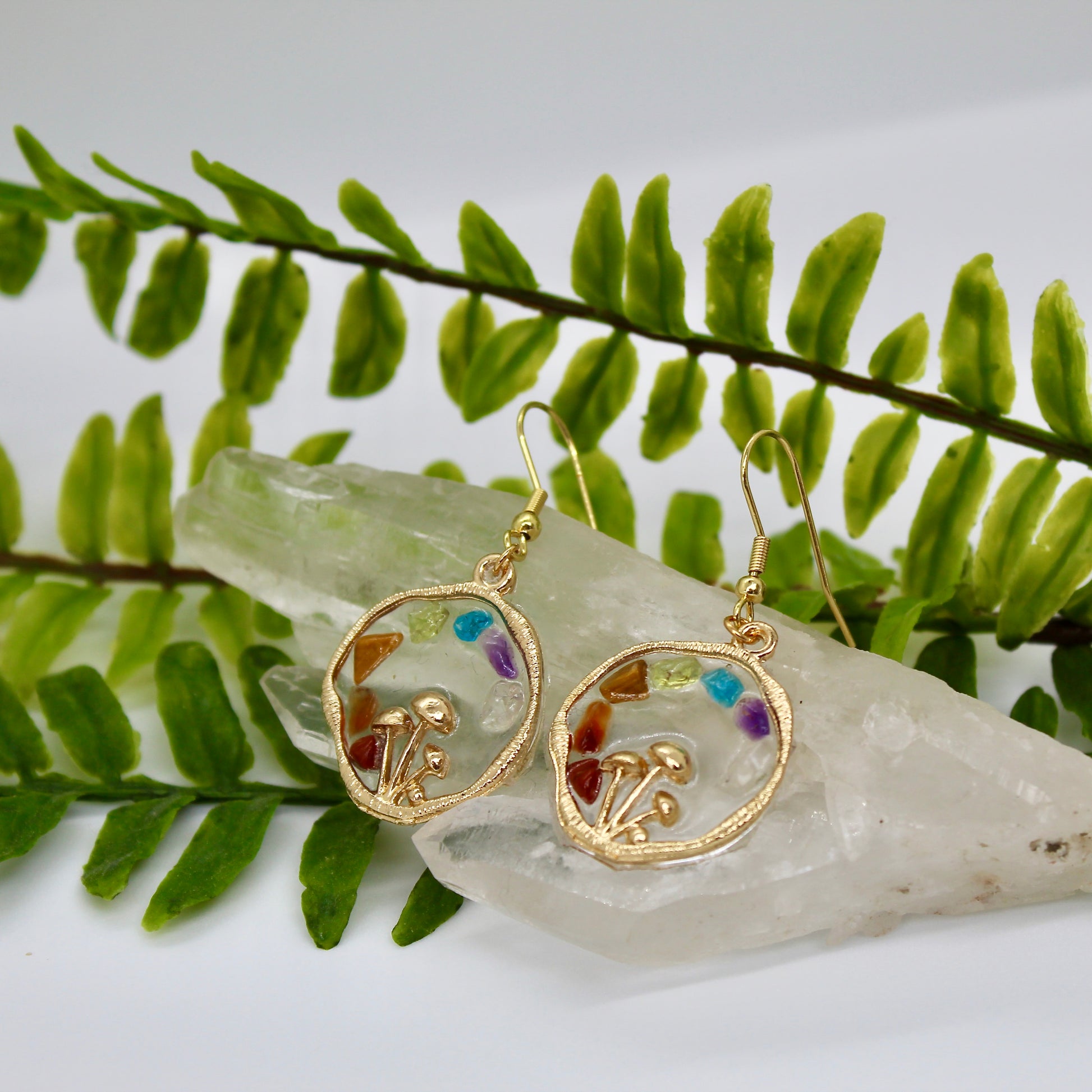 Chakra mushroom earrings with crystal chips display on crystal with plant background