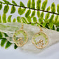 gold mushroom earrings with Peridot gemstone chips displayed on crystal