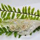 gold mushroom earrings with gemstone chips displayed on crystal 