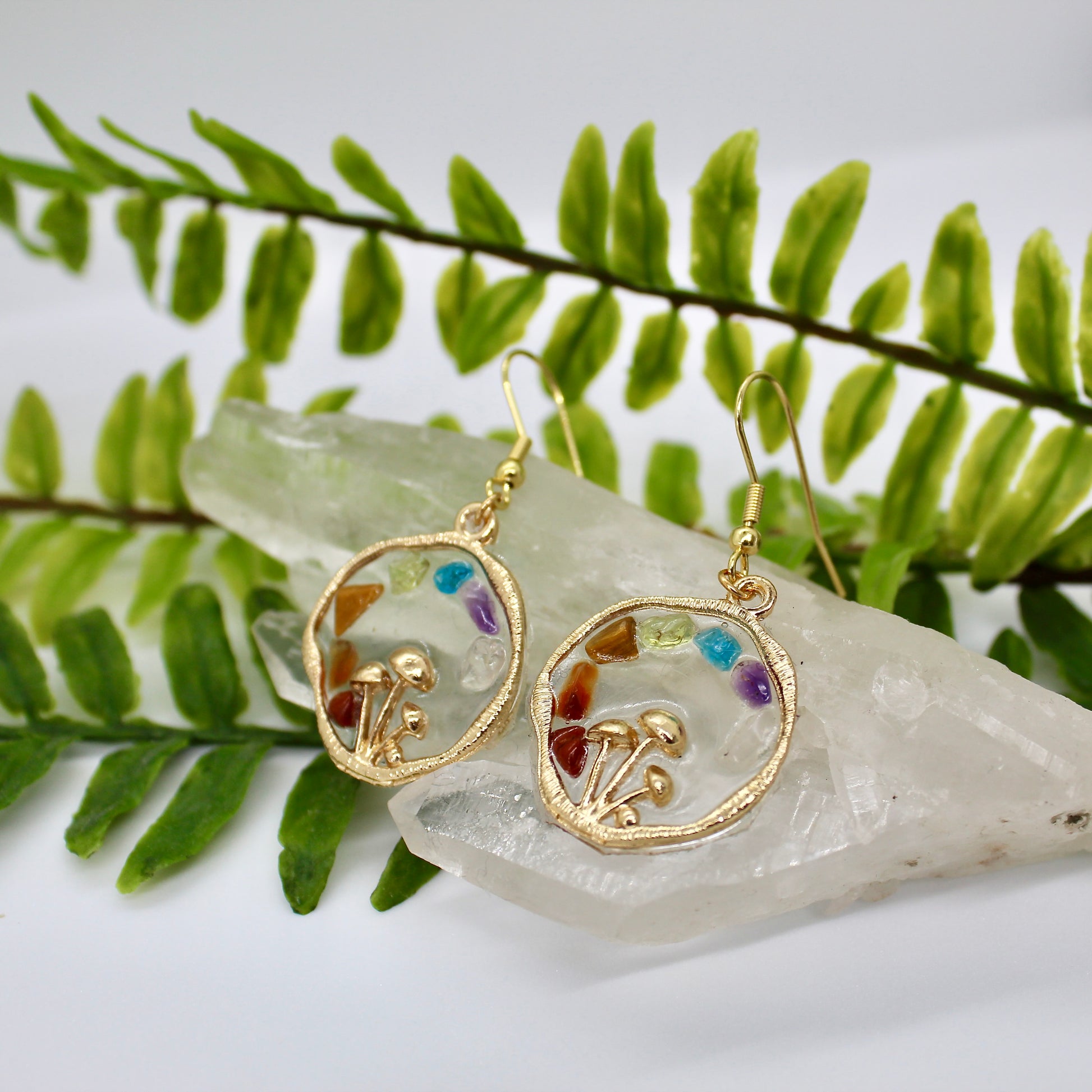 Chakra mushroom earrings displayed on crystal