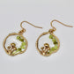 golden mushroom earrings with green gemstone chips on white background