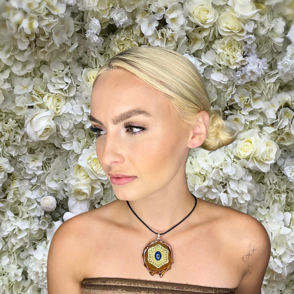 model wearing pinecone pendant with lapis stone and flower of life symbol on flower background 