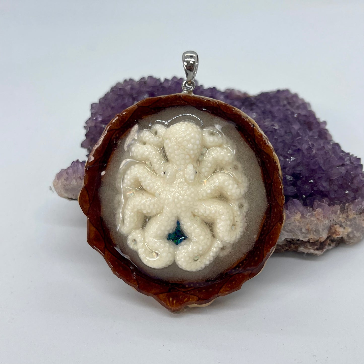 octopus pinecone pendant with crushed opal and silver bail displayed on crystal 