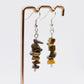 close up of tiger eye gemstone crystal dangle earrings on display stand 