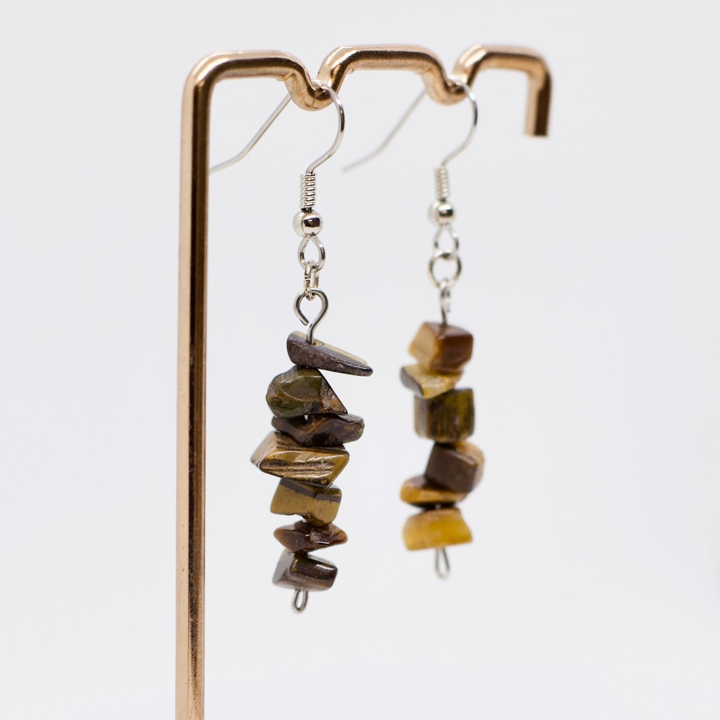 close up of tiger eye gemstone crystal dangle earrings on display stand 