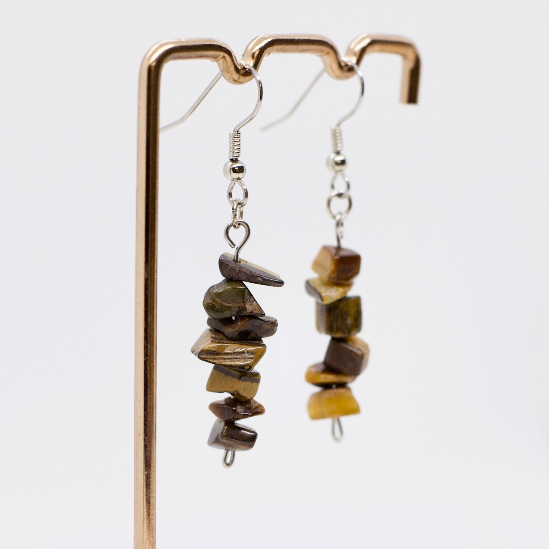 close up of tiger eye gemstone crystal dangle earrings on display stand 