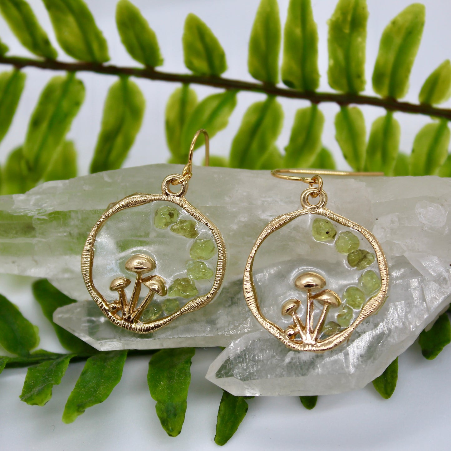 close up of green crystal earrings with gold mushrooms on crystal display 