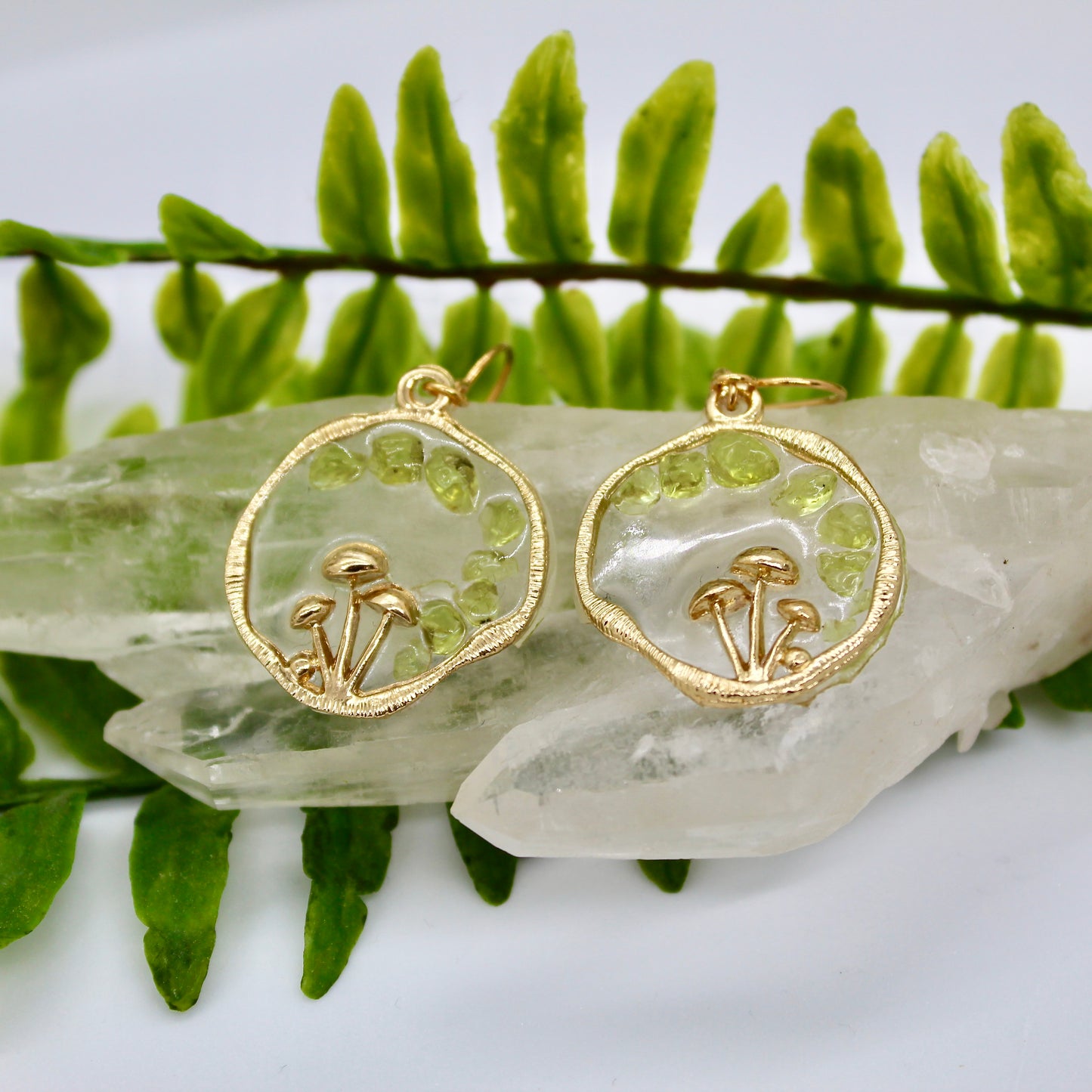 peridot gemstone gold mushroom earrings displayed on crystal 