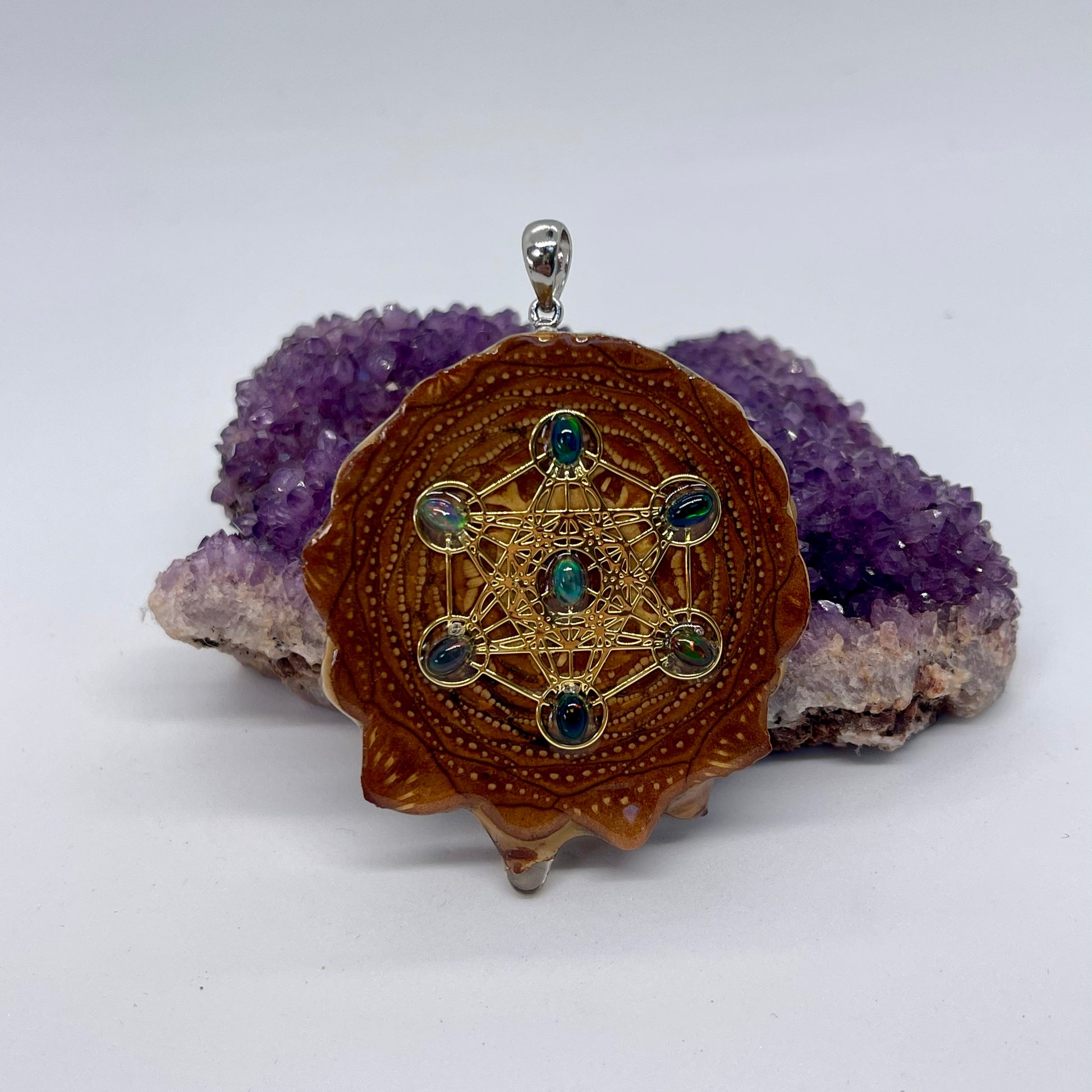 close up of pinecone pendant with black Fire Opals and Metatron's Cube symbol displayed on crystal