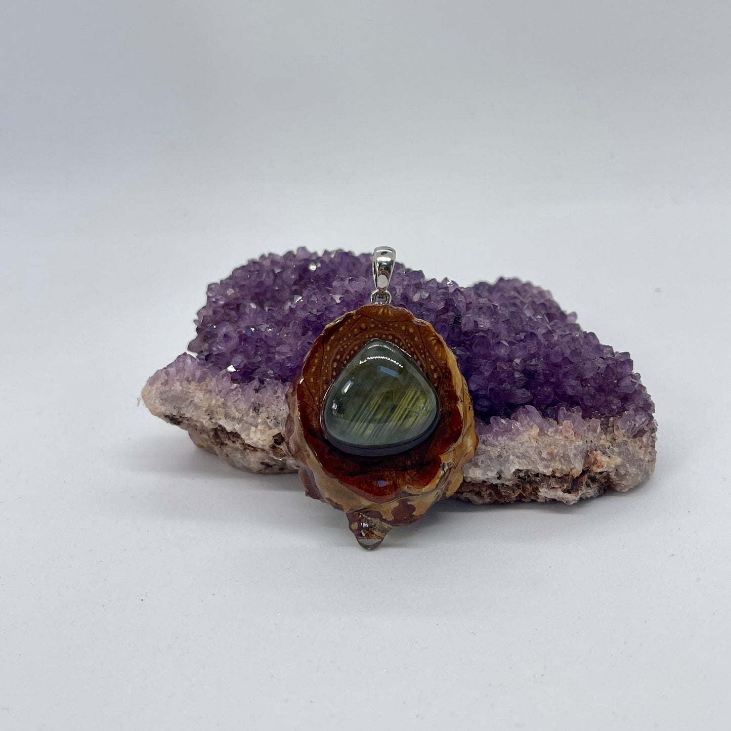 Pinecone pendant with teardrop labradorite gemstone displayed on crystal 