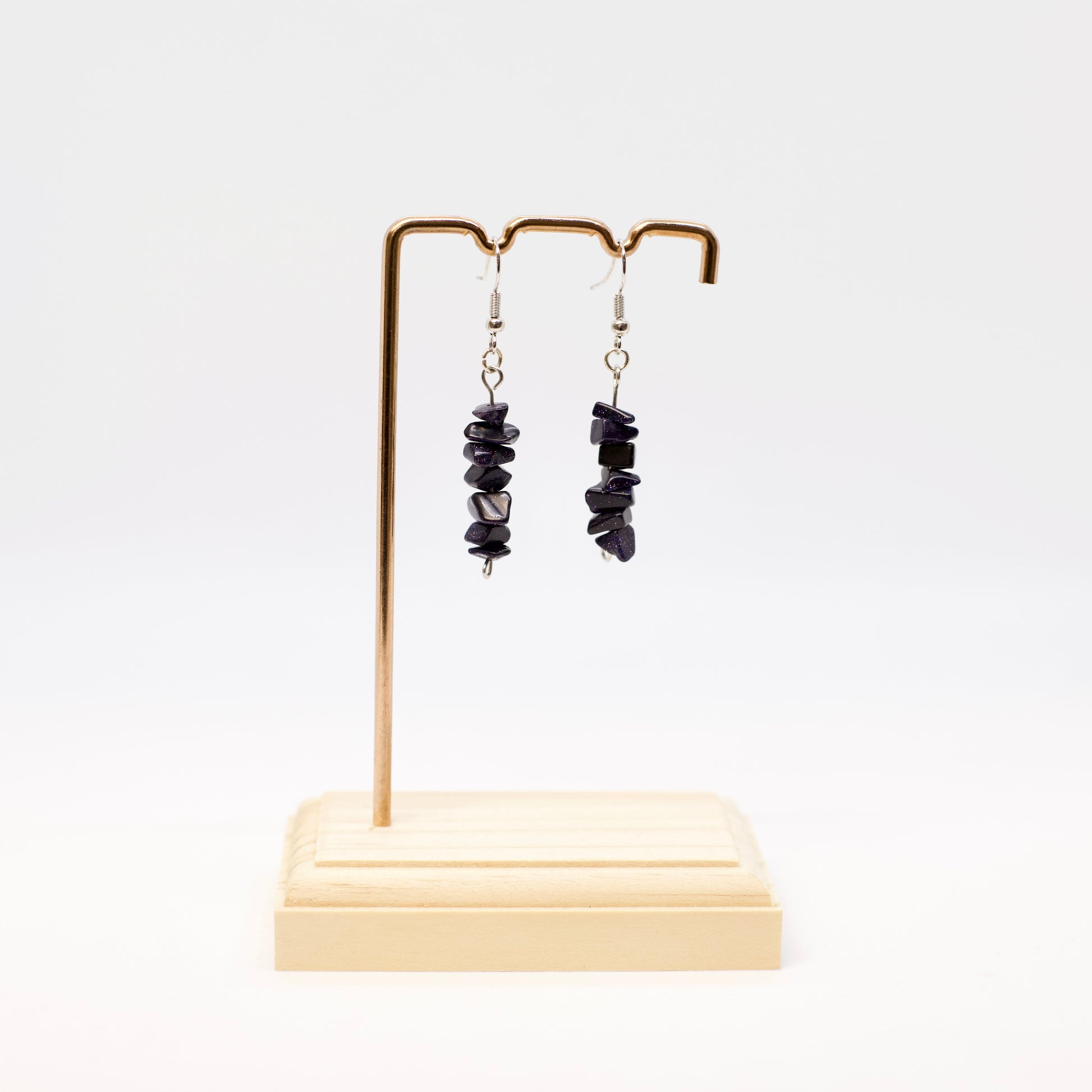 Blue Goldstone gemstone chip earrings on display stand with white background