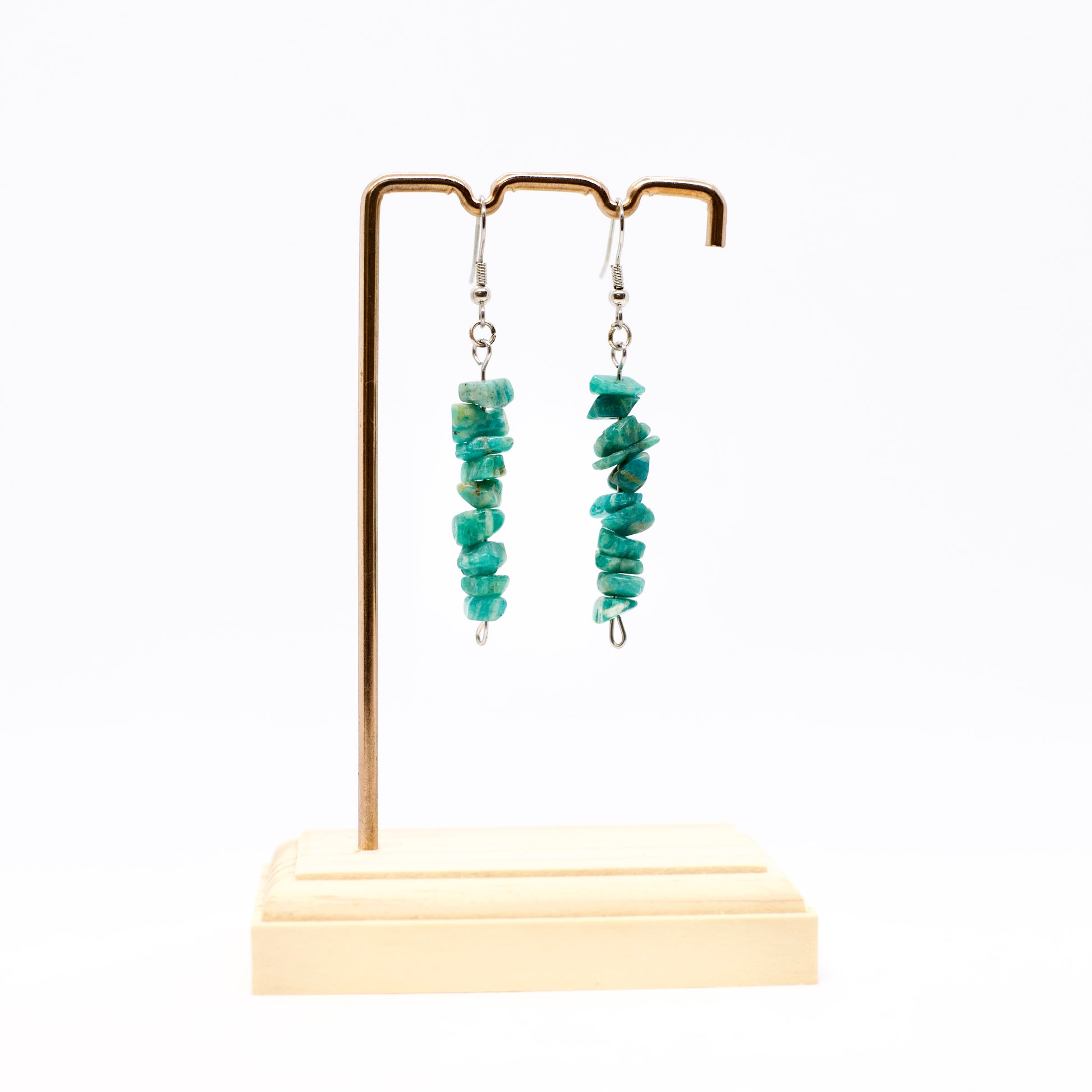 Amazonite gemstone dangle earrings on gold earring stand on white background
