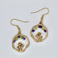 purple and green crystals in gold mushroom earring on white background