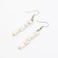 close up of howlite gemstone chip dangle earrings on white background