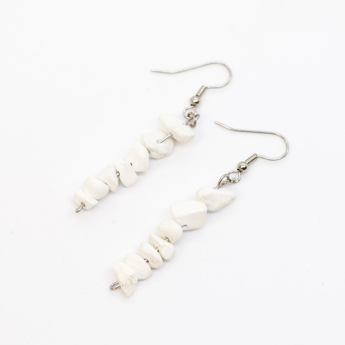 close up of howlite gemstone chip dangle earrings on white background