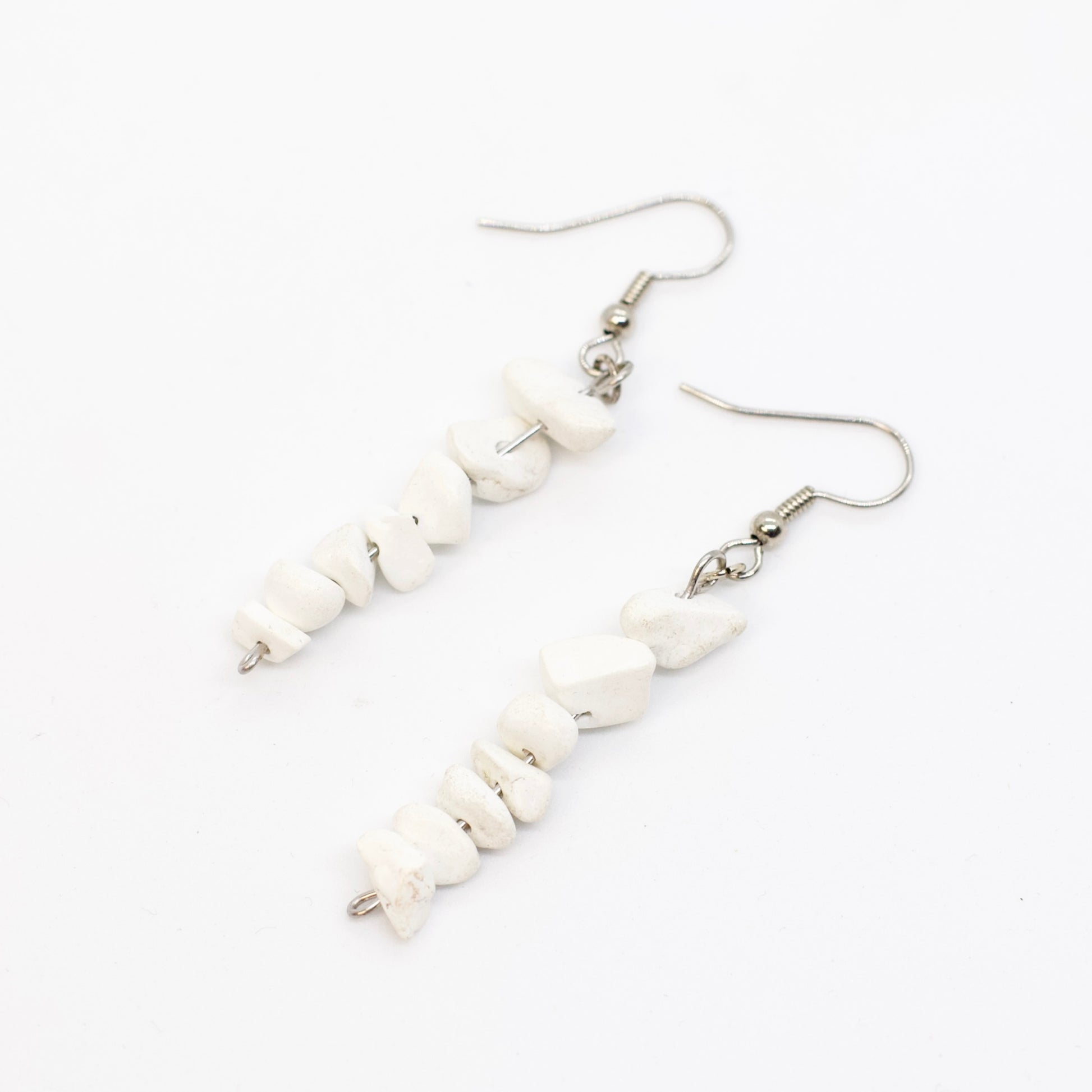 close up of howlite gemstone chip dangle earrings on white background
