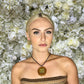 model wearing pinecone opal pendant in front of white flower background