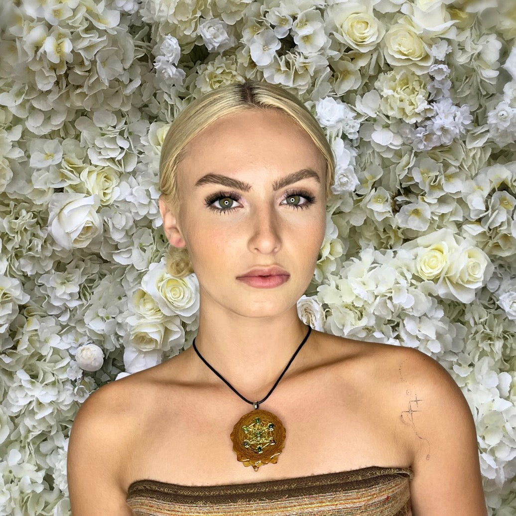 model wearing pinecone opal pendant in front of white flower background