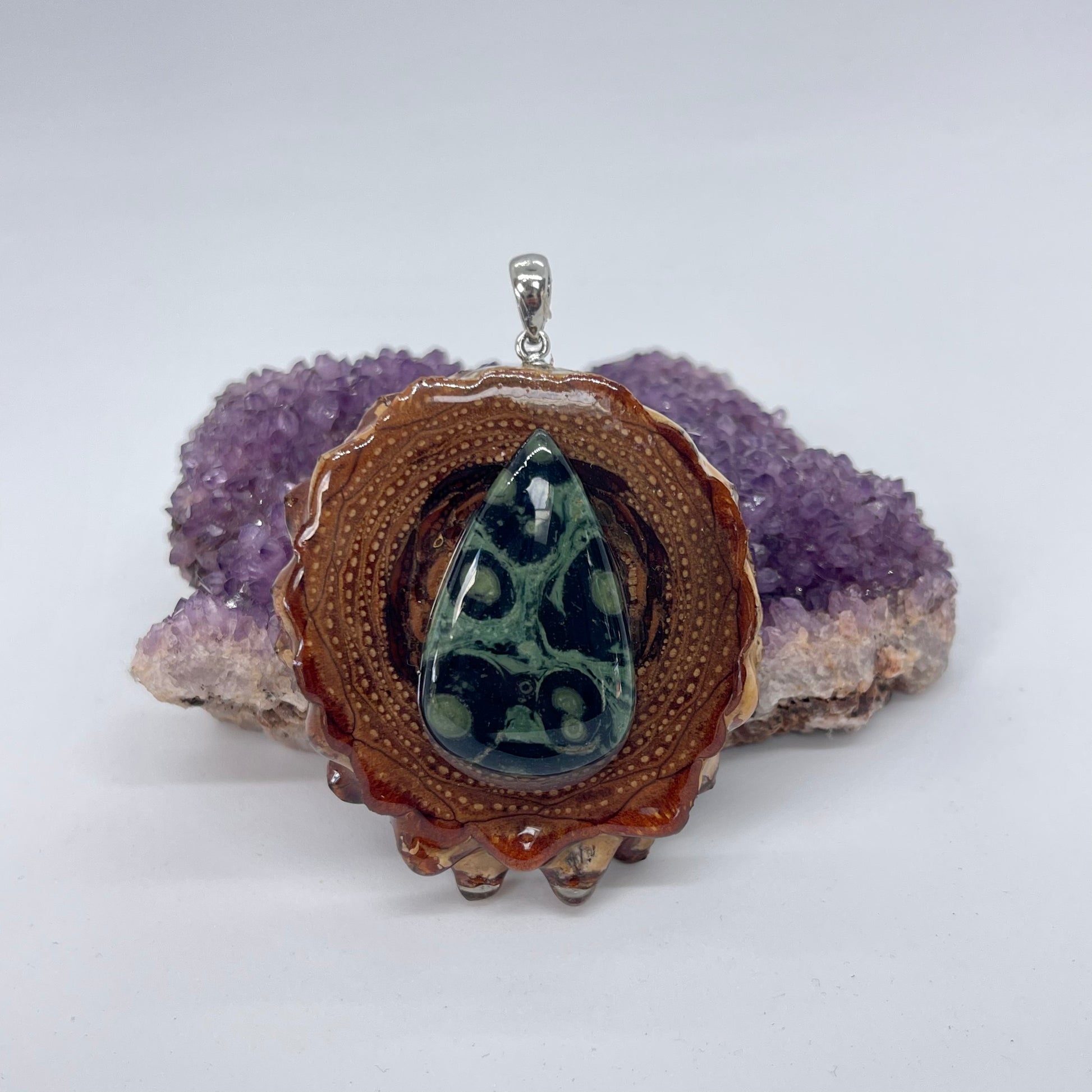 Pinecone pendant with Kambaba jasper stone displayed on crystal