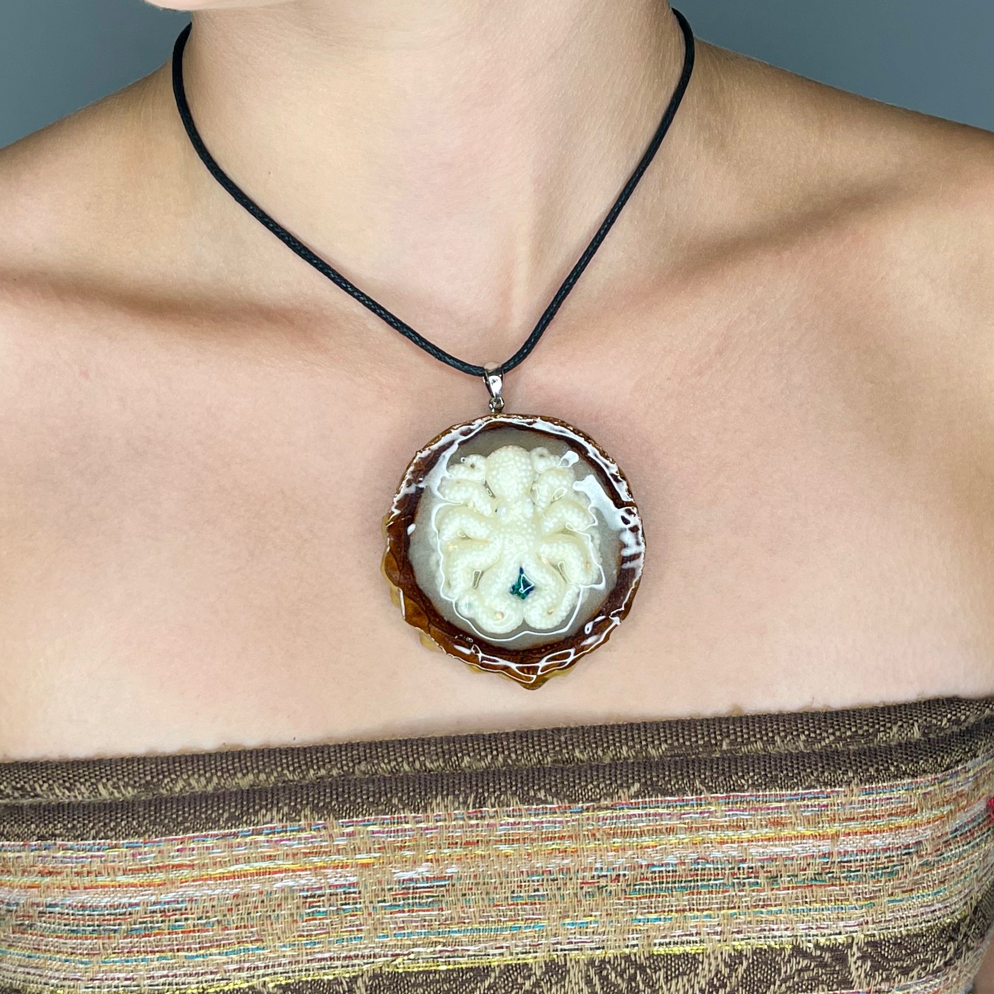 close-up of model wearing pinecone pendant with opal and octopus  