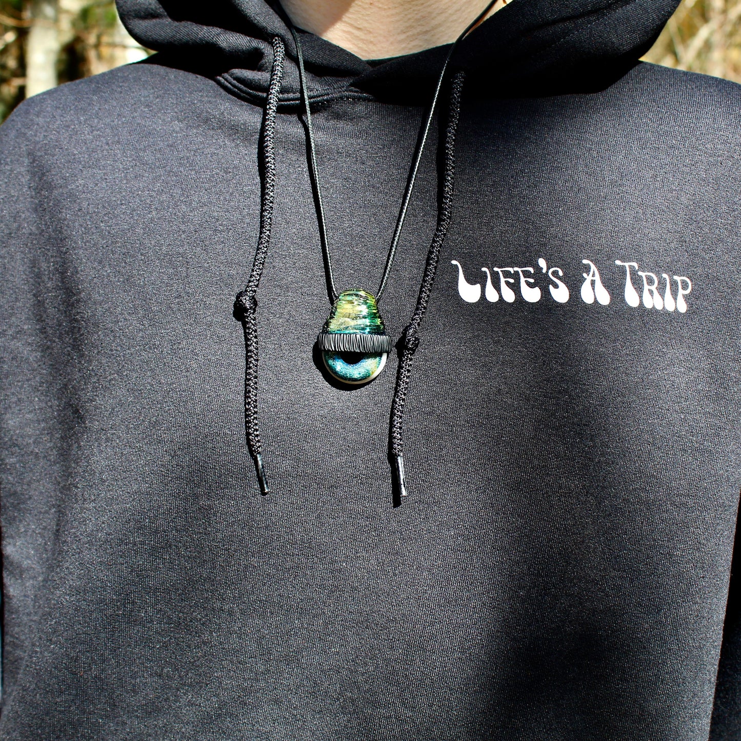 close up of model wearing black hoodie with life's a trip printed on front