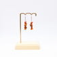 Carnelian gemstone chip dangle Earrings on display stand with white background