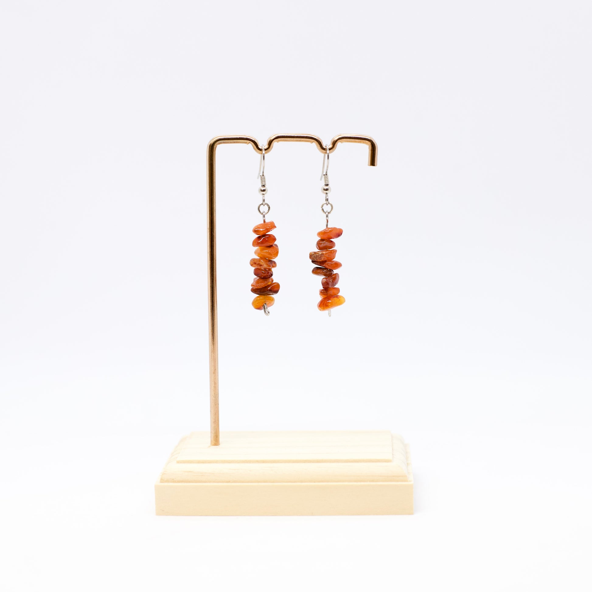 Carnelian gemstone chip dangle Earrings on display stand with white background