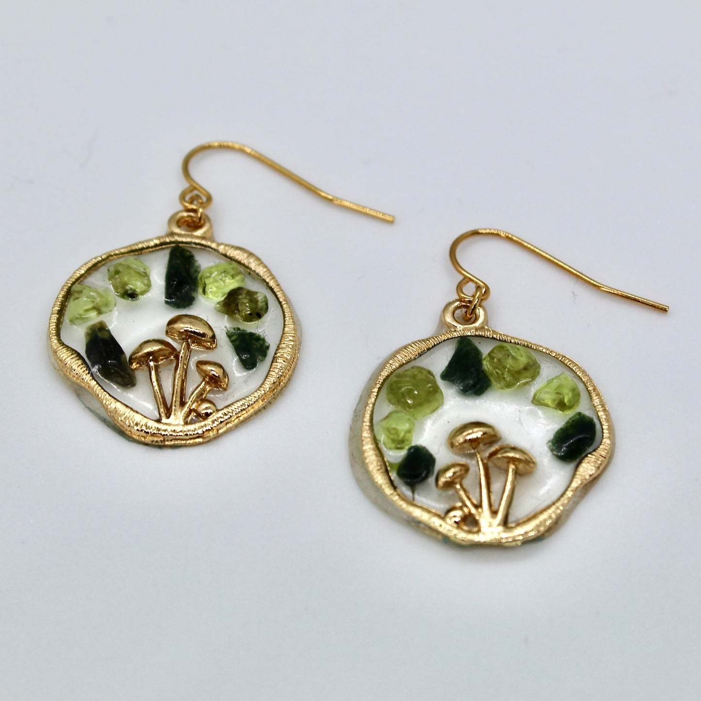 gold mushroom earrings with peridot and moss agate gemstone chips on white background 