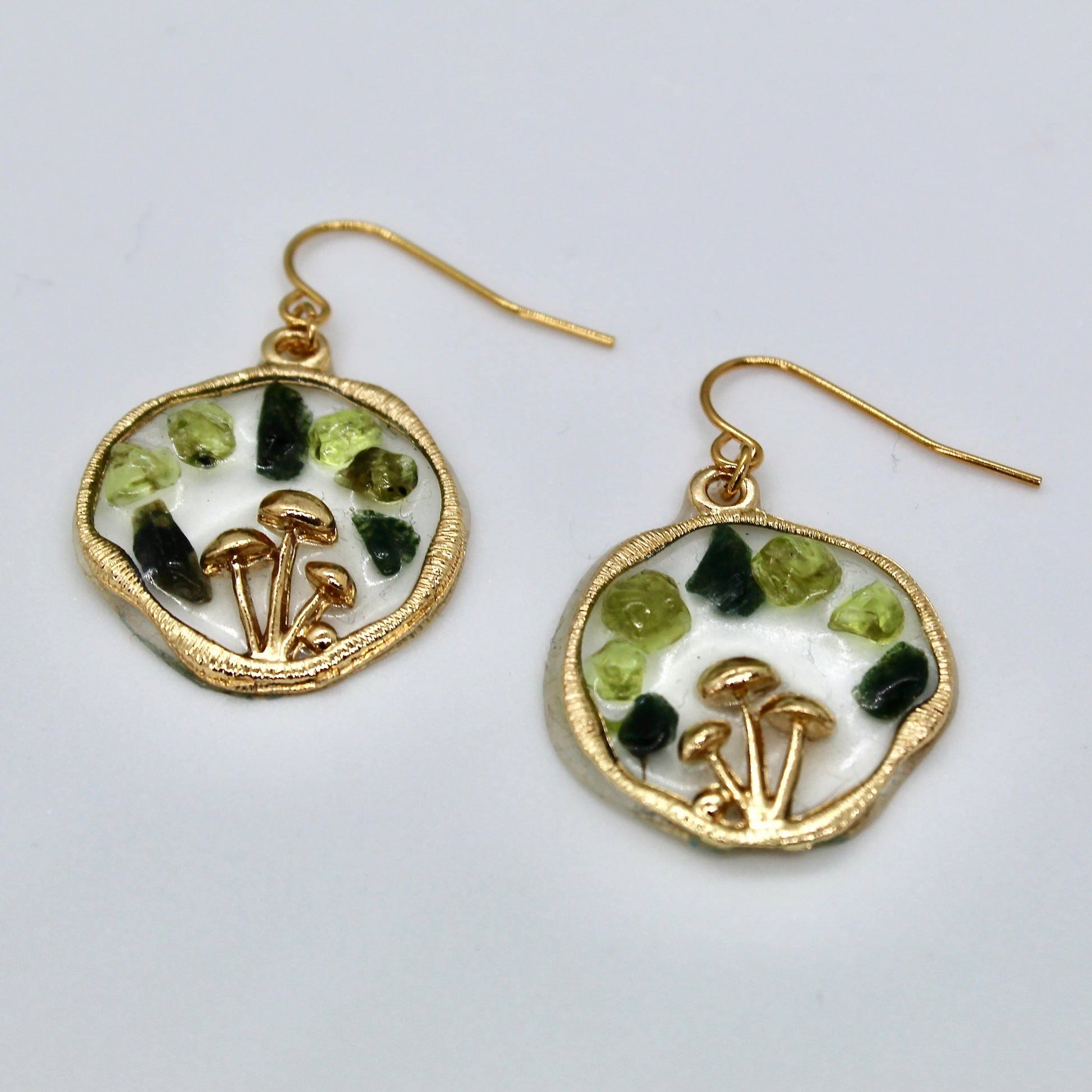 gold mushroom earrings with peridot and moss agate gemstone chips on white background 