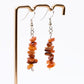 close up of Carnelian gemstone dangle earrings on display stand in front of white background 