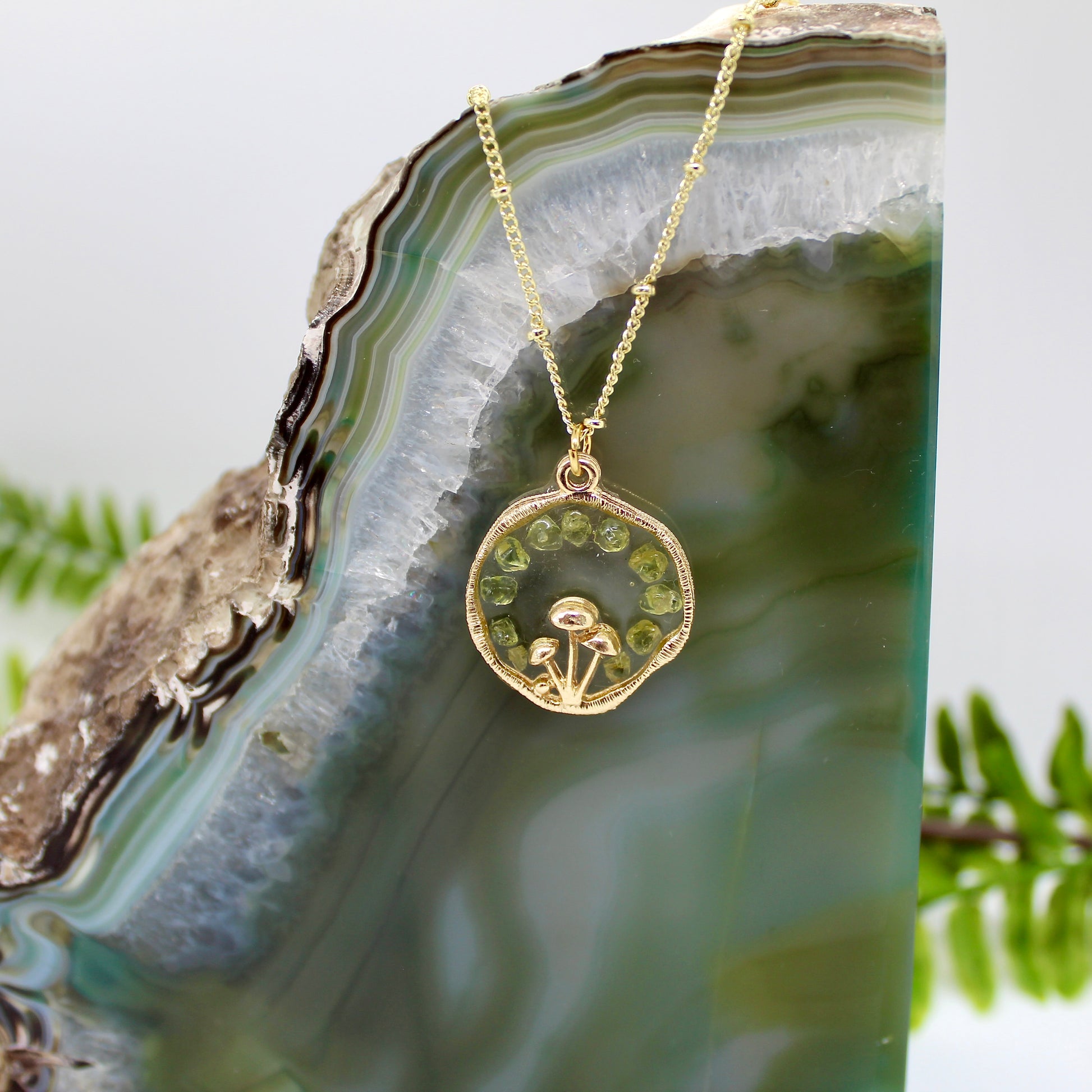 Gold msuhroom pendant with peridot gemstones on gold chain 