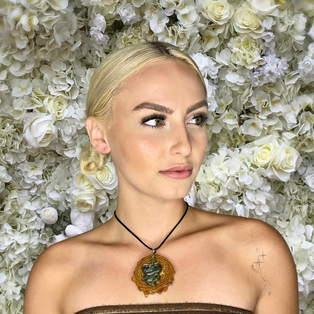 model wearing Labradorite snake pinecone pendant in front of flower background