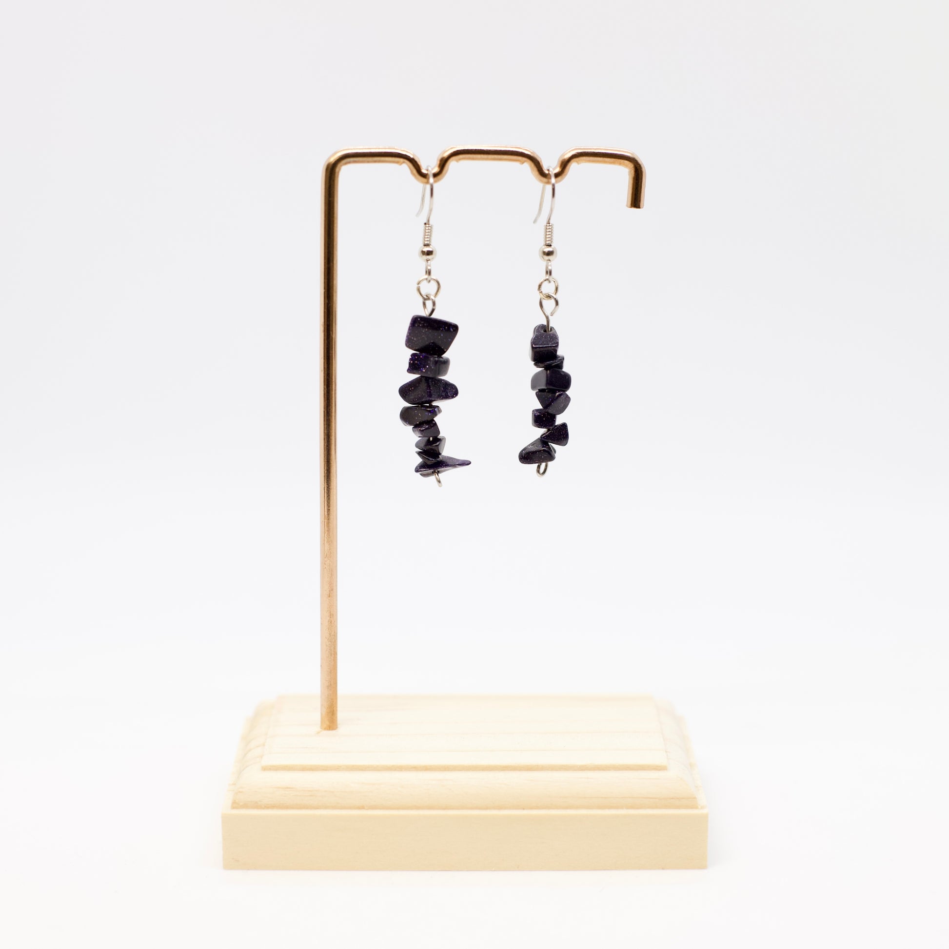 Blue Goldstone gemstone earrings on display stand with white background