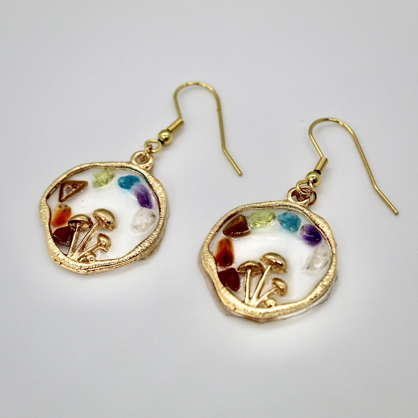 close up of chakra mushroom earring with crystals on white background